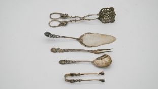 A collection of continental silver. Including sugar tongs, cake slice, sugar spoon and pickle
