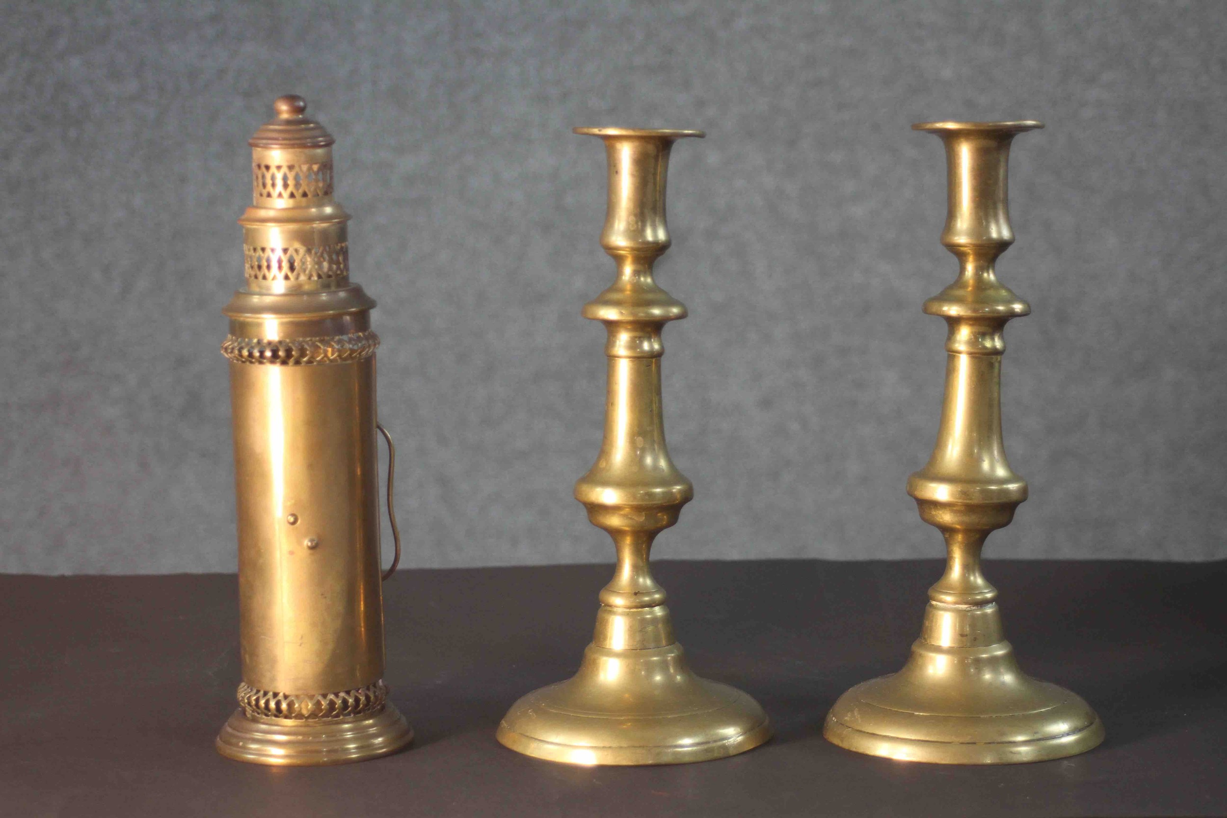 A pair of early 20th century brass candlesticks along with a portable brass candlestick lantern with