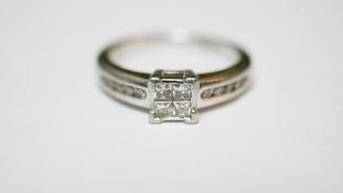 A platinum and diamond ring. Set to centre with four square princess cut diamonds in open back