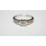 A platinum and diamond ring. Set to centre with four square princess cut diamonds in open back