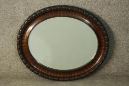 An early 20th century painted and lacquered framed oval wall mirror with bevelled plate. H.57 W.