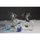 A collection of six art glass paper weights. A pair of dolphins balancing on balls, mum and baby