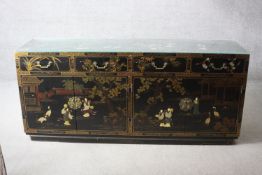 A mid century Chinese lacquered and hand decorated sideboard with four drawers above cupboards on