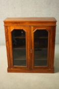 A Victorian walnut bookcase with glazed doors enclosing shelves on a plinth base. H.100 W.89 D.29cm.