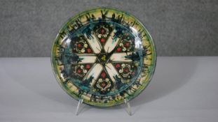A Persian green glazed ceramic dish, decorated with stylised floral motifs, marked and dated to