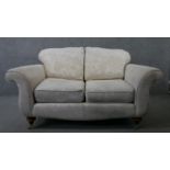 A two seater Victorian style scroll arm sofa in floral upholstery on turned supports terminating