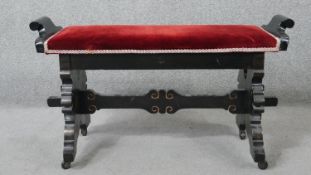 A late 19th century ebonised duet stool with stretchered lion carved supports. H.54 W.95 D.40cm