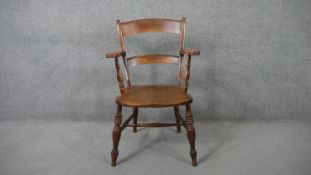 A 19th century elm seated country armchair on turned stretchered supports.