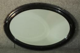 A Victorian ebonised framed oval wall mirror. H.87 W.61cm.