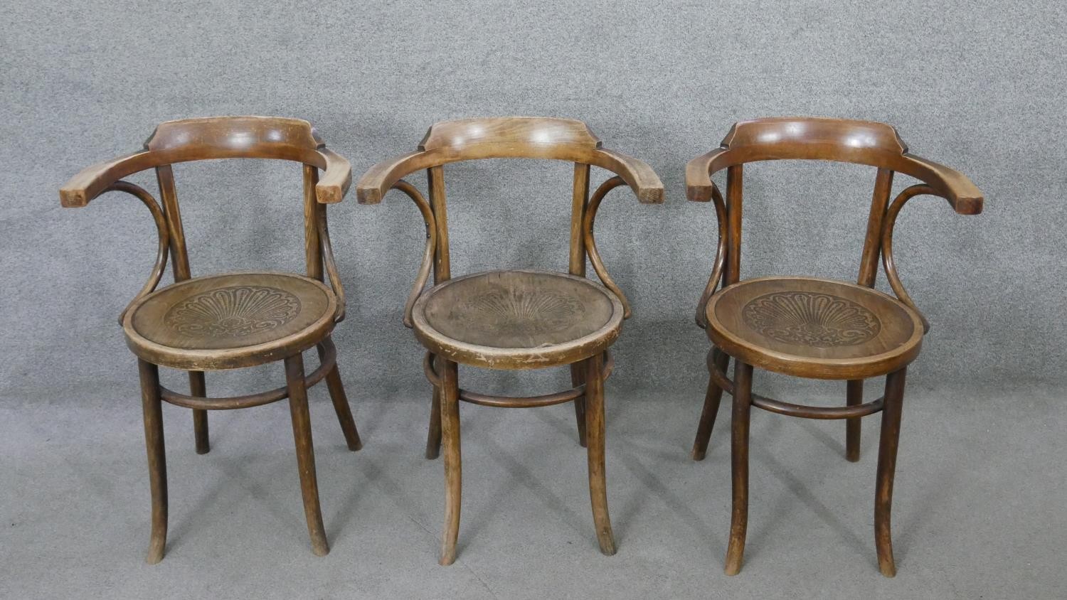 A set of three bentwood armchairs with floral embossed panel seats.