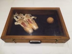 A vintage portable display vitrine containing a pair of signed Darcy Bussell point shoes and a