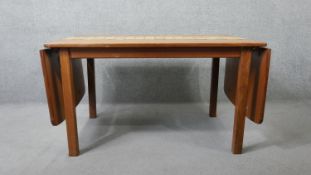 A 1960's vintage teak drop flap dining table with stoneware tile inlaid surface raised on square