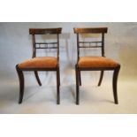 A pair of Regency rosewood dining chairs with brass inlaid bar backs and drop in seats on sabre