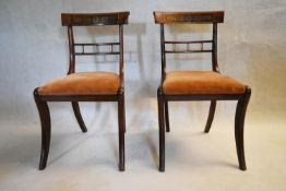 A pair of Regency rosewood dining chairs with brass inlaid bar backs and drop in seats on sabre