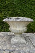 A weathered stone garden urn of flared and gadrooned form on pedestal base. H.50 W.63cm