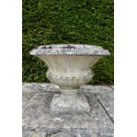 A weathered stone garden urn of flared and gadrooned form on pedestal base. H.50 W.63cm