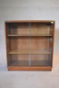 A mid century vintage teak bookcase with plate glass sliding doors on plinth base. H.75 W.62 D.27cm