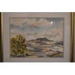 A framed and glazed watercolour of a hilly country landscape. Signed Wilfred Wilson. H.54 W.64cm