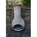 A painted terracotta chiminea with scrolling floral decoration.