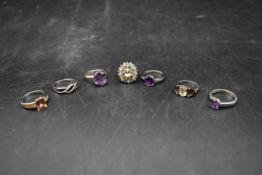 A collection of seven gemset silver rings. Including amethyst, topaz, black diamond and other