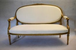A 19th century French carved giltwood canape with ribbon and floral carved back rail reupholstered