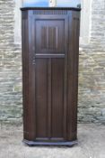 A mid century oak country antique style hall cupboard with linen fold panel door enclosing hanging