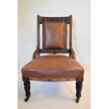 A late Victorian carved mahogany nursing chair in faux leather upholstery. H.95 W.63 D.63cm