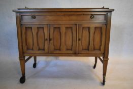 A walnut buffet cabinet with galleried top on square tapering supports terminating in wheel casters.