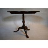 A Georgian mahogany tilt top table with baluster turned pedestal on tripod cabriole pad foot