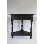 A late 19th century Jacobean style oak corner table on turned tapering supports united by undertier.