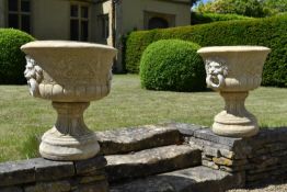 A pair of reconstituted stone two section garden urns with lion mask handles on pedestal bases. H.64