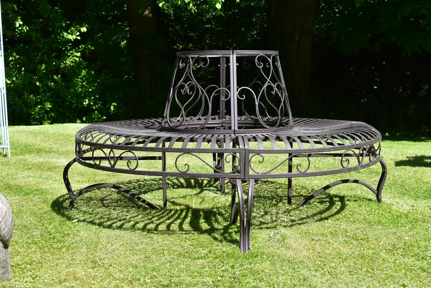 A wrought metal four section tree trunk bench with scroll decorated back and slatted seat. H.75