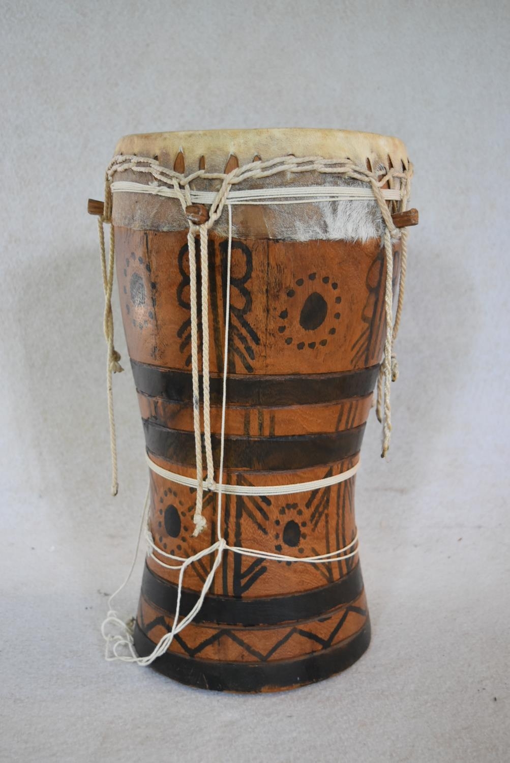 A Senegalese painted hardwood tribal drum. H.44 W.25cm