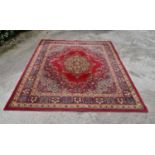 A Persian style carpet with central floral medallion on a burgundy ground contained by foliate