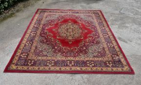 A Persian style carpet with central floral medallion on a burgundy ground contained by foliate