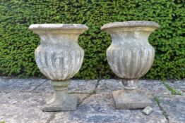 A pair of weathered garden urns of campana form. H.60 Dia.42cm (Damage and repairs as photographed).