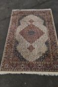 An Indian Agra carpet with triple floral pole medallions on a biscuit ground within spandrels and