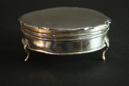 An 1920's hinged lidded silver box with scalloped edge and on tripod feet. Gilded interior and
