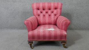 A 19th century mahogany framed armchair in deep buttoned upholstery on turned tapering supports