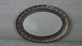 An early 20th century oval floral carved wall mirror with bevelled plate. H.70 W.93 D.6cm