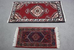 Two small Eastern rugs each on a red ground. L.110 W.60cm. (largest)