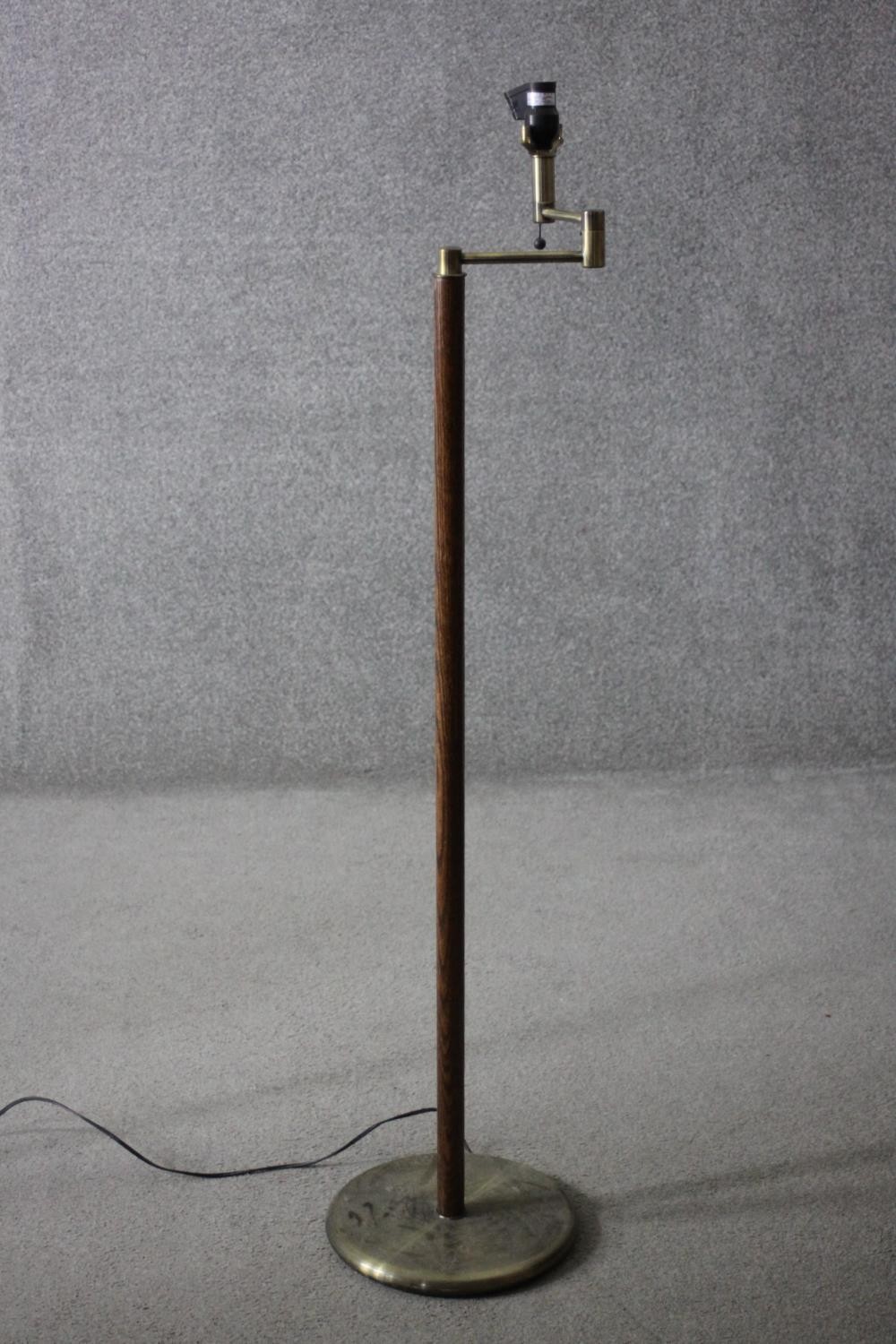 A vintage teak and brass standard lamp with hinged arm. H.134 Dia.30cm.