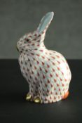 A Herend porcelain rabbit, in the red fishnet pattern, modelled in a seated position with gilded