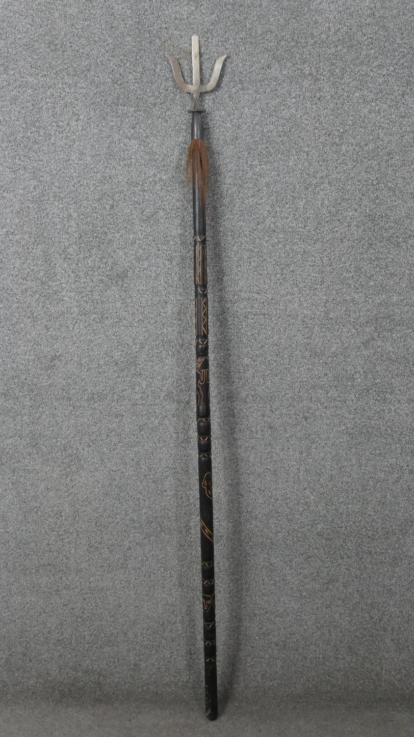A Polynesian hardwood and metal ceremonial staff with trident and animal hair detail. Carved