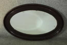 A Victorian ebonised framed oval wall mirror with bevelled plate. H.87 W. 61 cm.