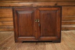 A 19th century teak cabinet with twin carrying handles and fielded panel doors enclosing a velvet