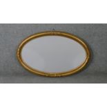 A C.1900 oval wall mirror in gilt ribbon and beaded gesso frame. H.50 W.78cm