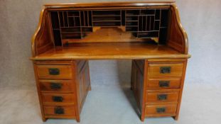 An American style teak roll top desk with fitted pigeon hole interior on pedestal bases fitted