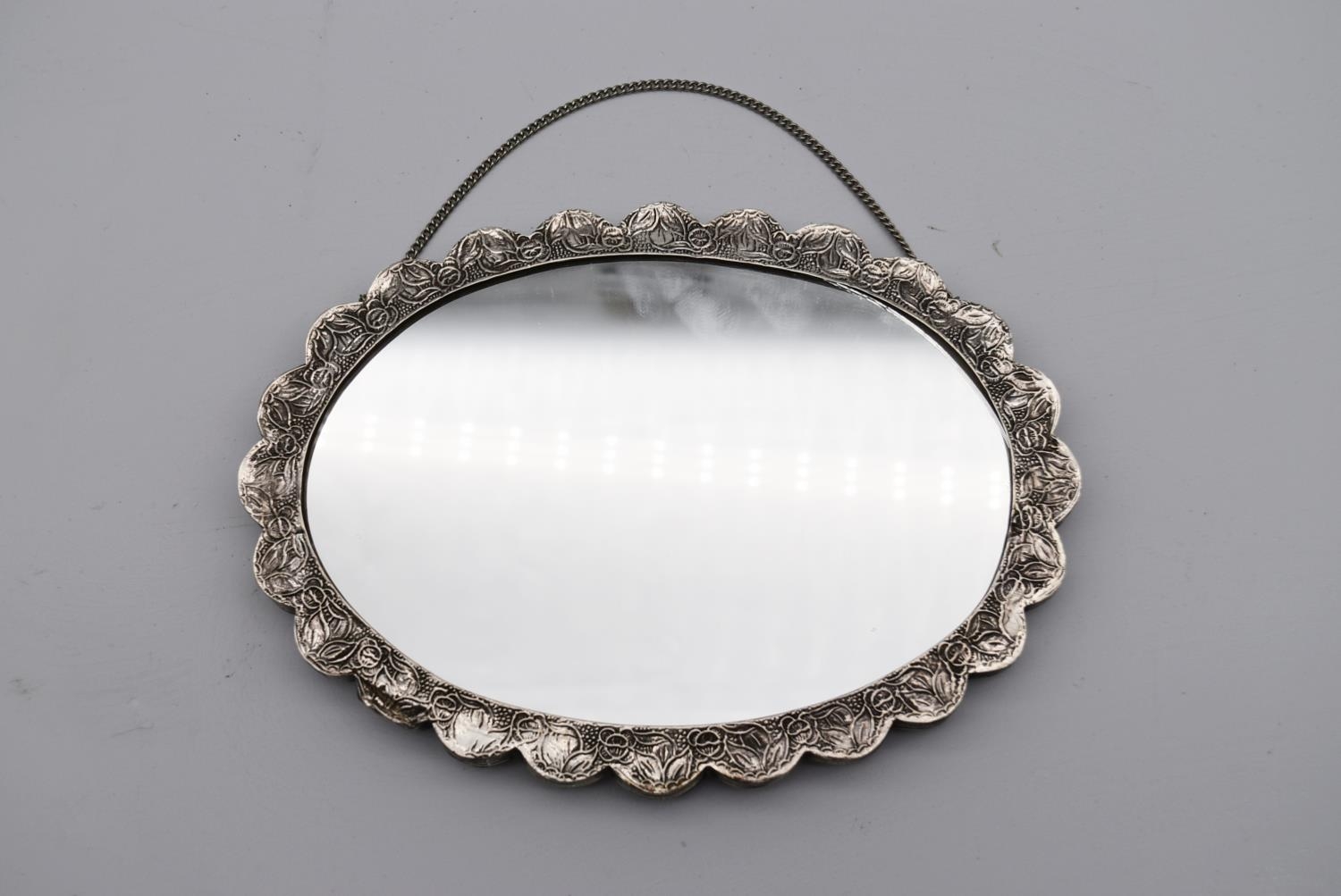 A 20th century Indian silver repousse mirror with stylised foliate and floral design and hanging