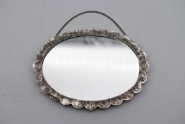 A 20th century Indian silver repousse mirror with stylised foliate and floral design and hanging